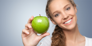 woman smiling holding an apple